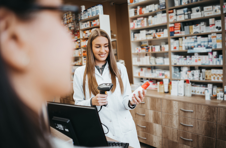 Woman pharmacist in drugstore using bar code reader on a product.