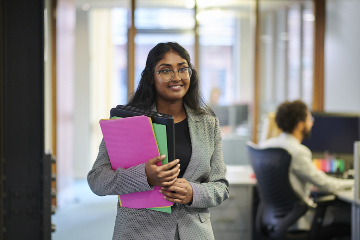 happy young office worker with folder and files in her arms.
