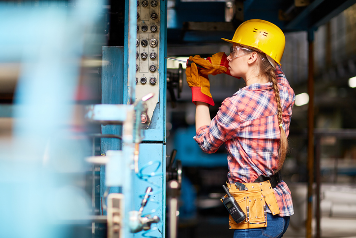 Young woman in uniform repairing something with screwdriver
