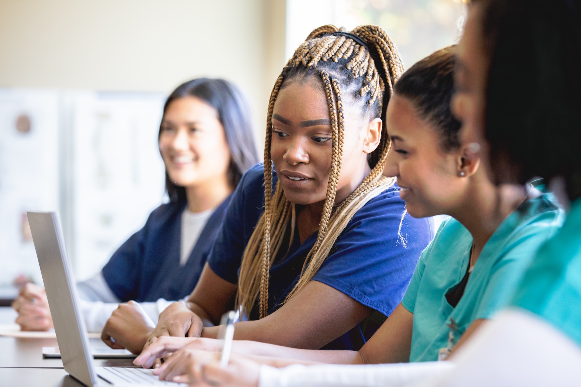 Diverse group of women looking at a laptop in class.